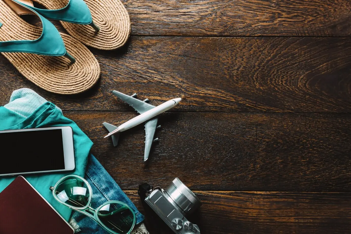 Draufsicht auf Reisezubehör mit Mobiltelefon, Kamera und Sonnenbrille.